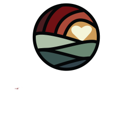 A circular logo with stylized hills and a sun containing a heart shape. Text below reads Lake Country Caring and Basic Needs Met By Caring Hearts.